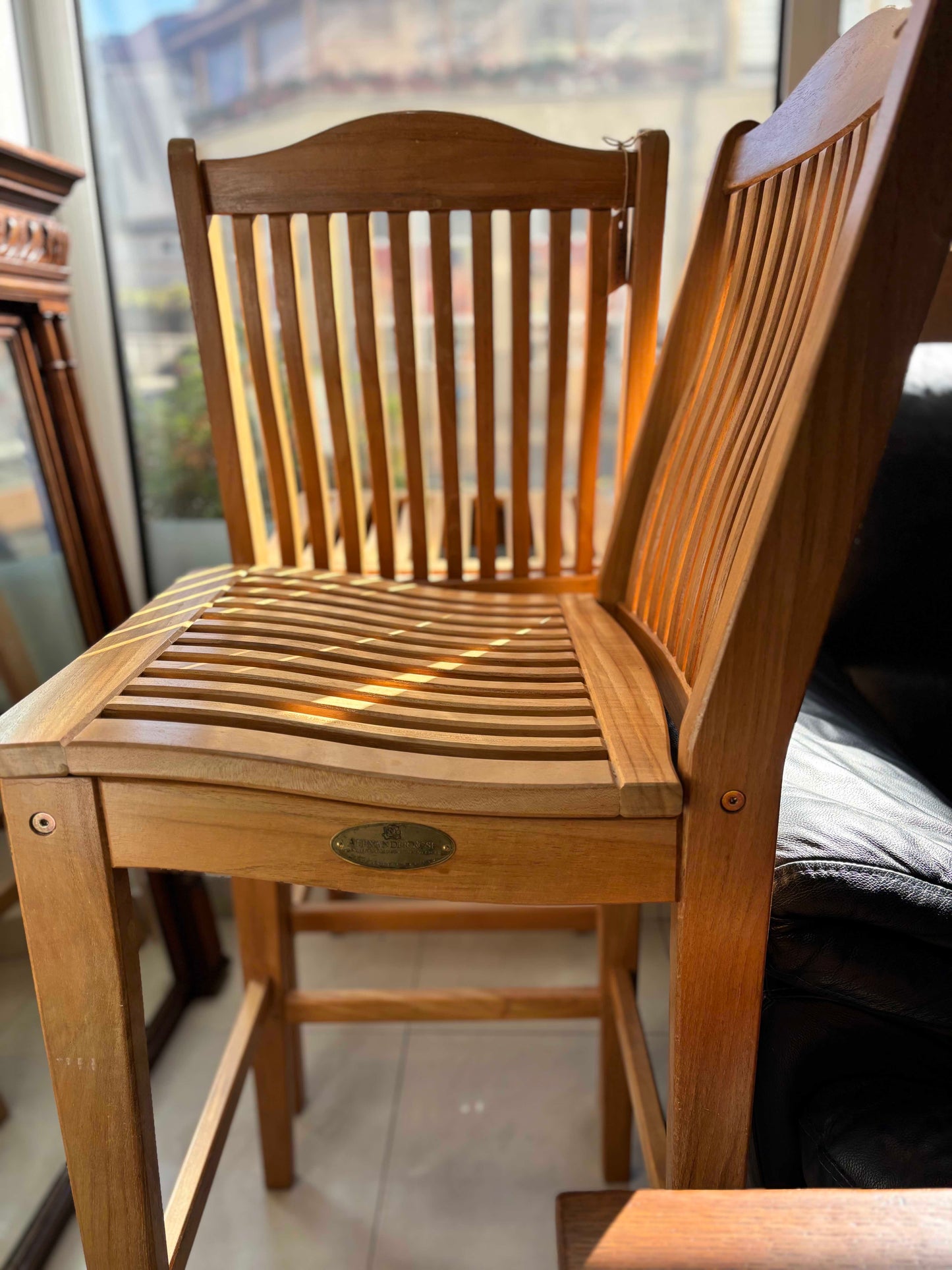 Set of tall wooden bar chairs with sleek, natural wood finish, featuring sturdy legs, a curved backrest, and a footrest for added comfort. The minimalist design complements a rustic or modern bar setting.